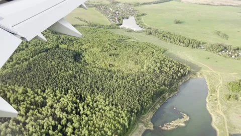 View from the window of the plane with green lands and buildings on the earth Stock Footage 263297315