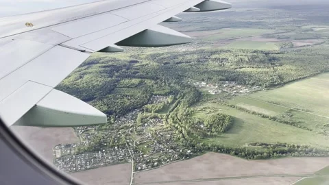 View from the window of the plane with green lands and buildings on the earth Stock Footage 263297317