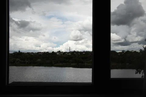 A view from a window of a river, trees, and residential buildings under thick Stock Photos
