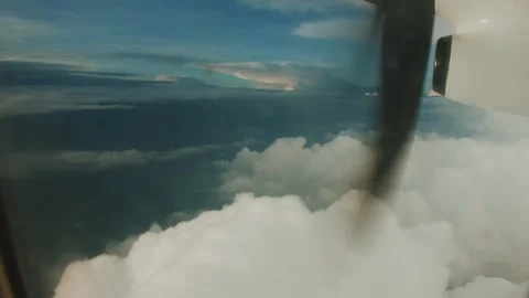 View from window of turboprop plane to white fluffy clouds and pieces of earth Stock-Footage 265448138