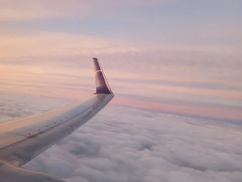 View from the window of the wing of an airplane flying over the sea of ​​clouds Stock Photos