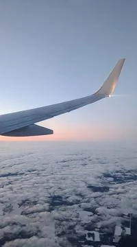 View from the window on the wing of an airplane with a light bulb on, blue sk Stock Photos