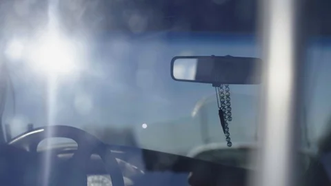 View of a windshield and a dangling bullet casing and bracelet Stock Footage 92104140