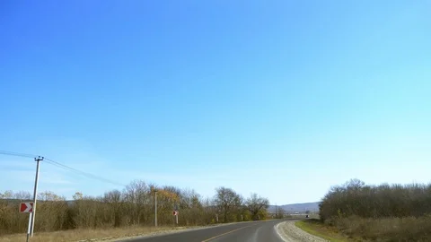 View from the windshield of a car. On a sunny day, an empty road runs between Stock Footage 119542886