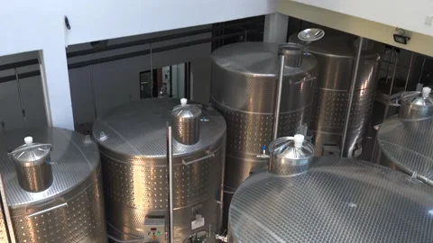 View of winery fermentation equipment in building with large metal tanks Video stock 219263097