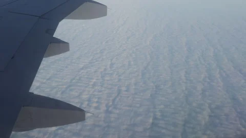 View of wing of airplane flying at high altitude on fluffy clouds. View from Stock Footage 295806211