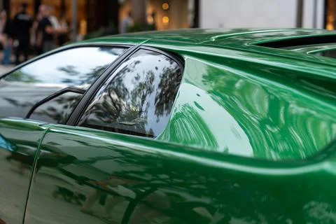 View on wing and driver window of bright two door car parked on crowded street Stock Photos