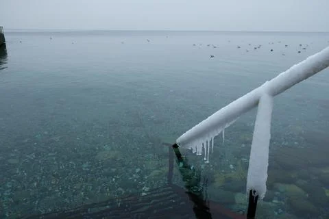 View of the winter beach with snow, an empty frame under umbrellas Stock Photos