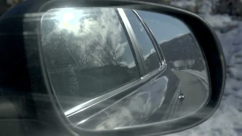 View of the winter road in the rearview mirror of a car. Sun in the clouds Stock Footage 96433091