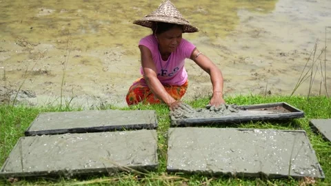 View of a woman in a conical hat working with mud, Bangladesh. Video stock 334982054