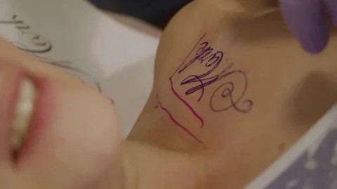 View of woman's body part with tattoo design on it and blur of woman's face who Stock Footage