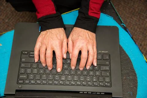 View of woman's hands typing on a black keyboard laptop. Stock Photos