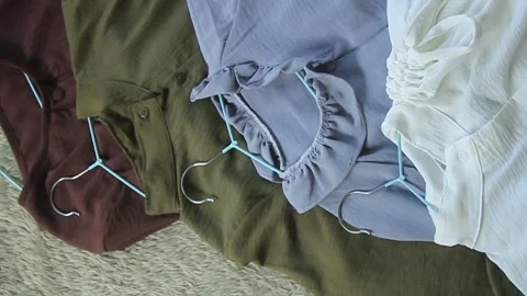 View of women's blouses of various colors from above with hangers attached. Video stock 280104906