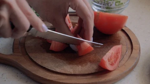 View of women's hands cutting tomatoes on a cutting board in the kitchen. Stock Footage 112879435