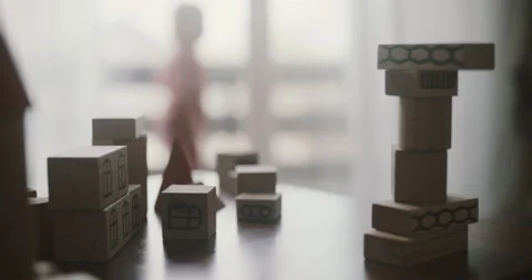 View of wooden blocks on the table in front of window, blurred childs silhouette Stock Footage 155810900