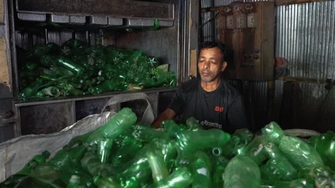 View of a worker recycling green plastic bottles in Bogura, Bangladesh. Stockbeeldmateriaal 336424431