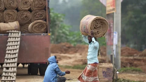 View of workers carrying large jute rolls on their heads, Bangladesh. 스톡 동영상 334973340