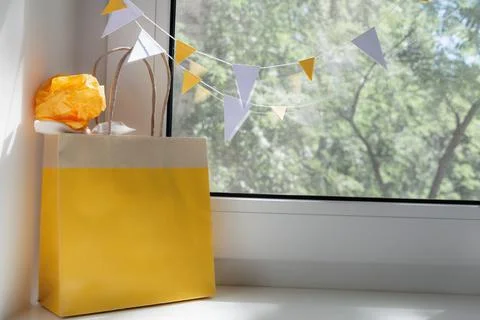 View of the yellow bag with a gift on the window. Holiday concept, background Stock Photos