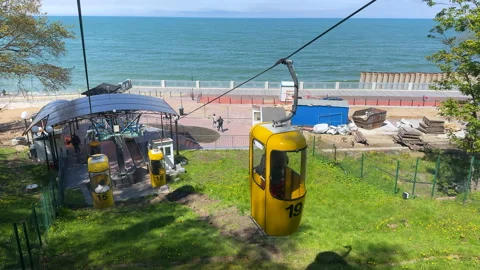 View of yellow funicular cabins descending toward the sea, carrying people down  库存影片 310836366