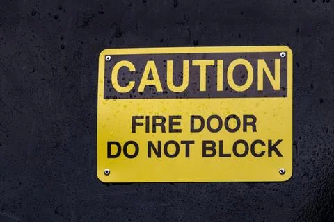 View of yellow sign Caution Fire Door Do Not Block Stock Photos