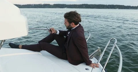 View of a Young attractive business man using smartphone on a yacht or boat Stock Footage