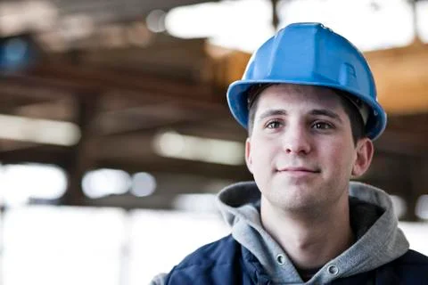 View of a young caucasian factory worker wearing a hard hat in a factory. Stock Photos
