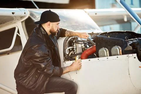 View of young engineer sitting with instruments near light airplane Foto stock