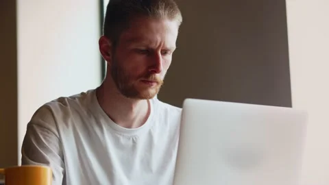 View of a young frowning programmer who is busy writing code for a mobile Stock Footage 237182939