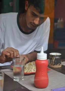 View of a young guy eating fast food in the cafe seen through the window glass.  Stock Photos