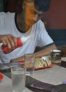 View of a young guy eating fast food in the cafe seen through the window glass.  Stock Photos