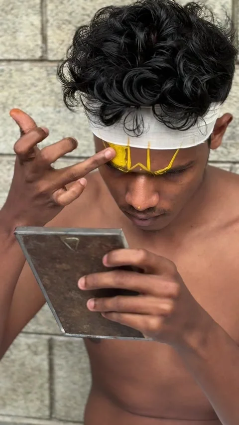 View of a young man applying traditional yellow face paint in Kochi, India. Stock Footage 334997006