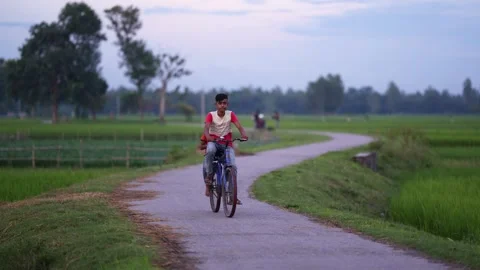 View of a young man riding a bicycle on a rural path, Bangladesh. Video stock 335584477