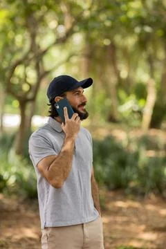View of young man using a smartphone at day time with a green park in the bac Stock Photos
