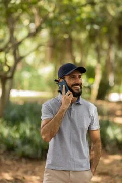 View of young man using a smartphone at day time with a green park in the bac Stock Photos