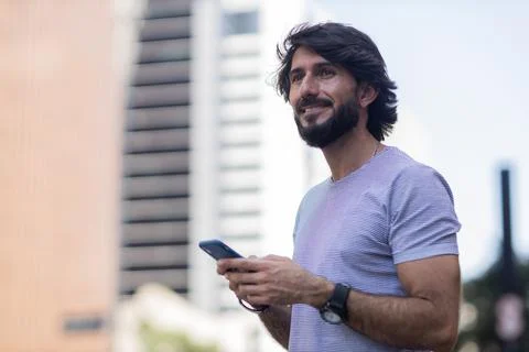 View of young man using a smartphone at day time with city view landscape in  Stock Photos
