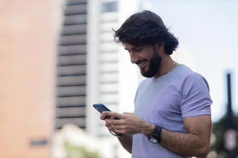 View of young man using a smartphone at day time with city view landscape in  Stock Photos