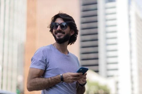 View of young man using a smartphone at day time with city view landscape in  Stock Photos