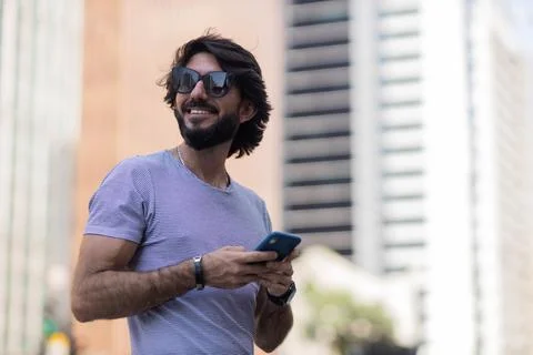 View of young man using a smartphone at day time with city view landscape in  Stock Photos