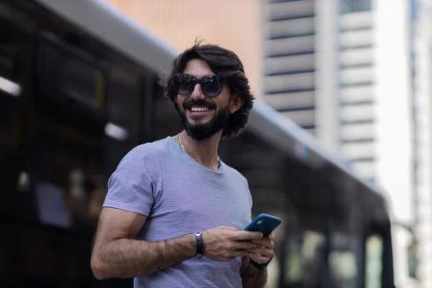 View of young man using a smartphone at day time with city view landscape in  Stock Photos