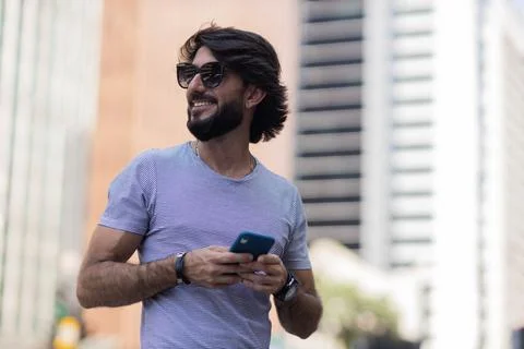 View of young man using a smartphone at day time with city view landscape in  Stock Photos