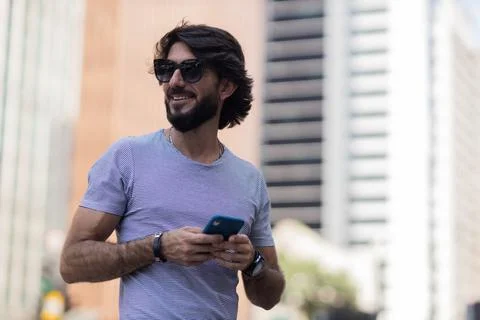 View of young man using a smartphone at day time with city view landscape in  Stock Photos