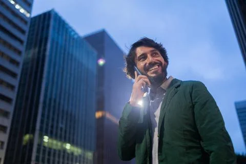 View of young man using a smartphone at night time with city view landscape i Stock Photos