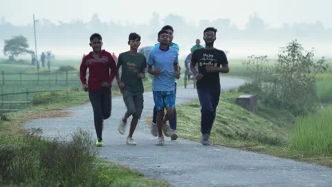 View of young men jogging on a misty rural road, Bangladesh. Video stock 335550369