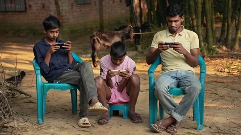 View of young men using smartphones in a rural village, Bangladesh. 動画素材 335024958