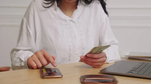 View of young woman sits while counts dollar money at table. Woman calculat.. Stock Footage 266470735