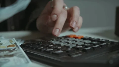 View of young woman sits while counts dollar money at table. Woman calculating Stock-Footage 336259973