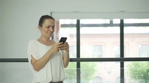View at young woman using mobile phone in the modern office interior 4K Stock Footage 135687978