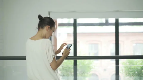 View at young woman using mobile phone in the modern office 4K Stock Footage 135689315