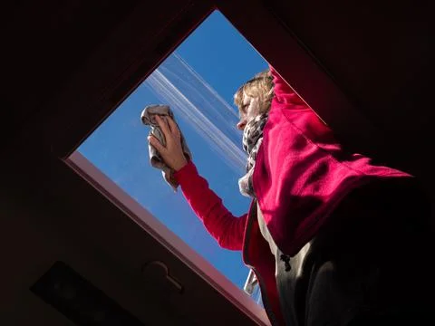 Viewed from below a lady cleans a skylight window of her recreational vehicle Stock Photos