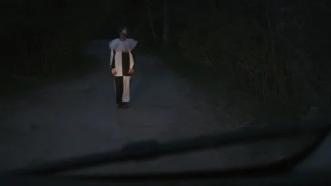 Viewer Seeing Scary Clown Standing in Middle of Road from Car Window Stock Footage 250963575